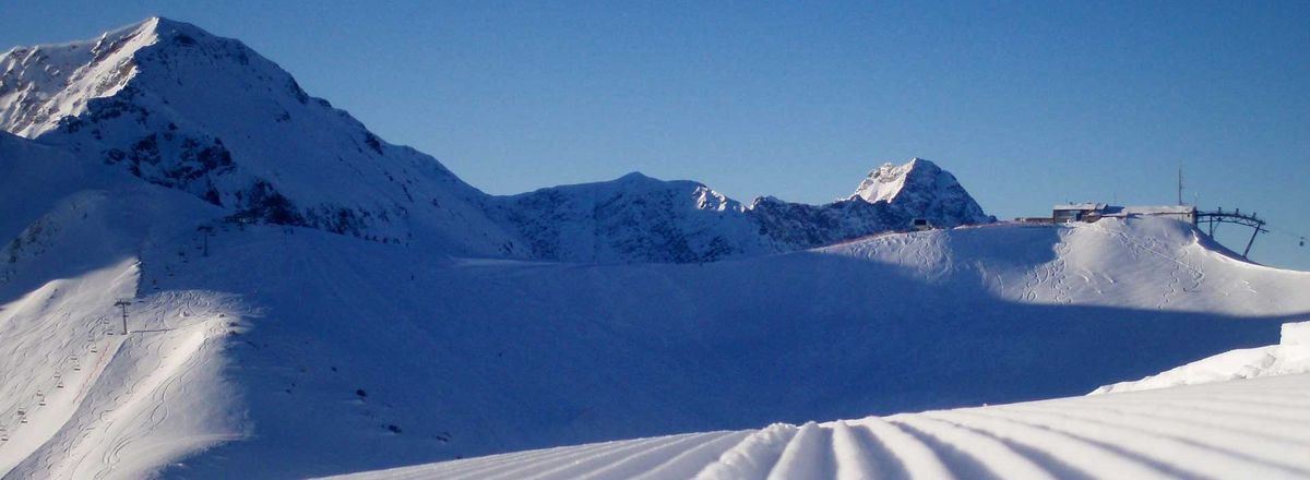 Frisch präparierte Skipiste mit Spuren und Bergkulisse im Hintergrund