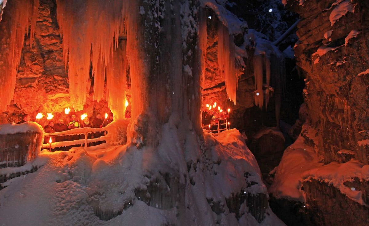 Beleuchtete Eishöhle mit Fackelwanderung im Winter
