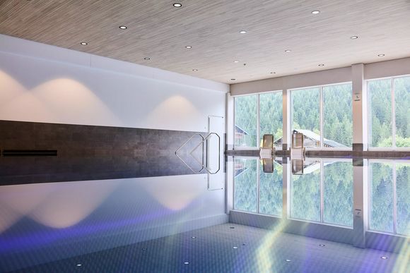 Modernes Hallenbad mit großen Panoramafenstern und Blick ins Grüne