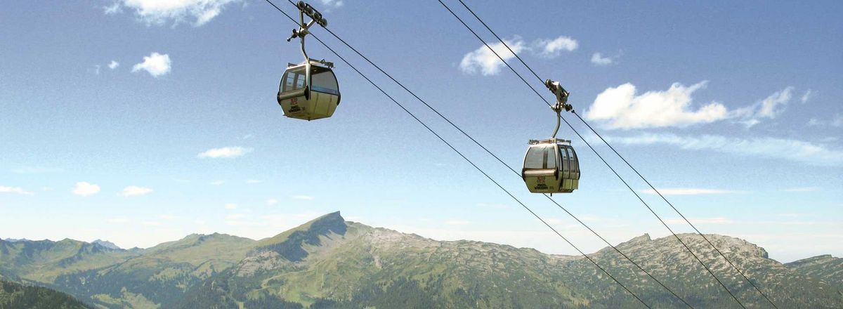 Zwei Gondeln einer Seilbahn über einer grünen Berglandschaft