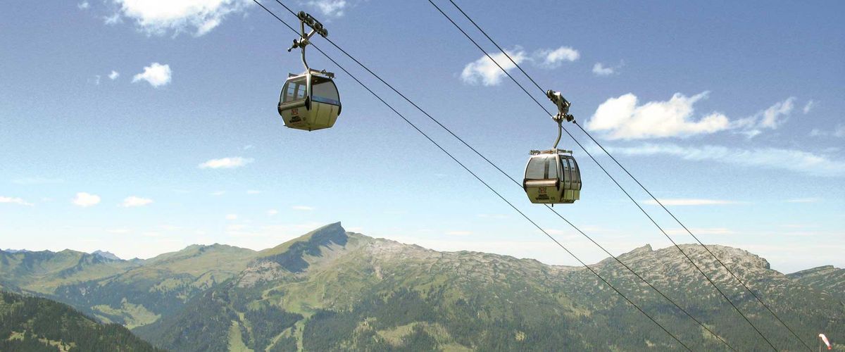 Zwei Gondeln einer Seilbahn über einer grünen Berglandschaft
