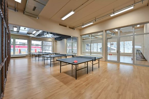 Indoor-Bereich mit Tischtennisplatten und Sportboden