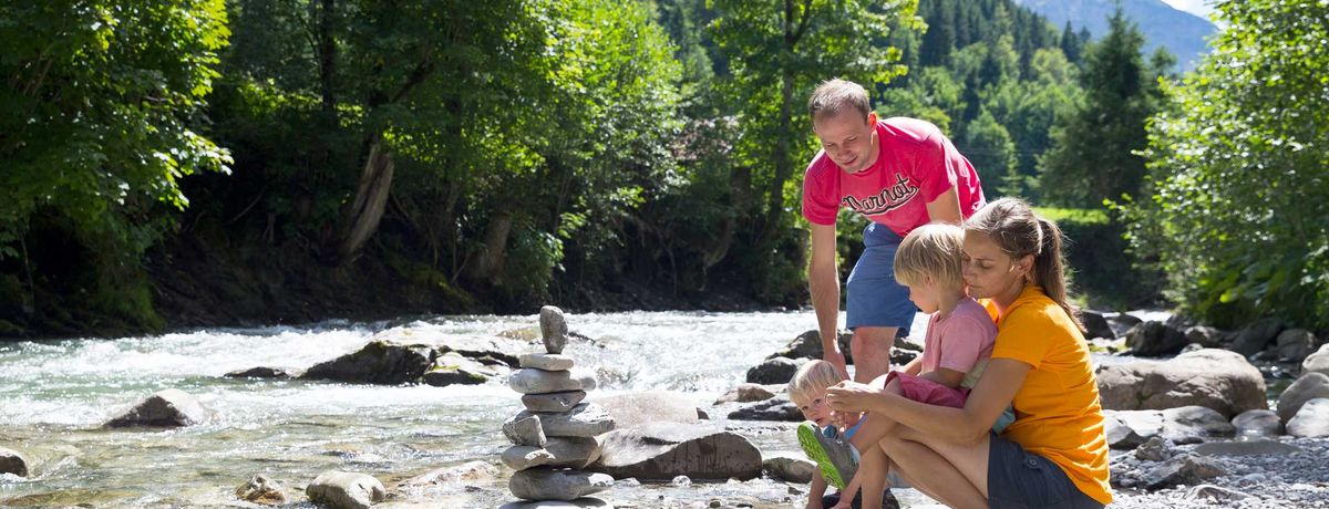 Familie baut einen Steinturm am Flussufer