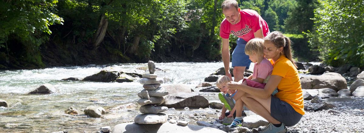 Familie baut einen Steinturm am Flussufer
